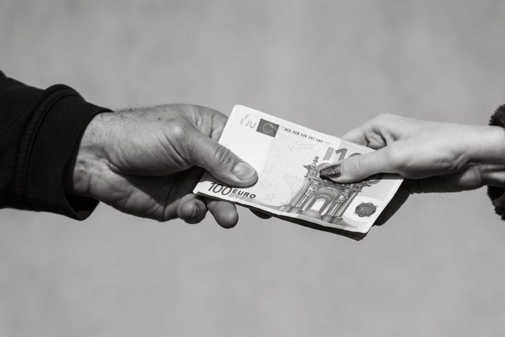 Greyscale Shot Of A Woman's Hand Holding And Giving Money To A Man